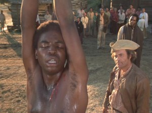 Kunta Kinte being whipped, Roots (1977) screenshot, July 6, 2012. (http://irvine.wikis.gdc.georgetown.edu). Qualifies as fair use under US Copyright laws because of screenshot's low resolution.