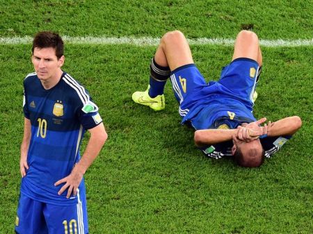 Argentina's Pablo Zabaleta lies on the pitch as Lionel Messi stands beside him after losing to Germany in the final, Rio de Janeiro, Brazil, July 13, 2014. (Francois Xavier Marit/AP via http://usatoday.com).